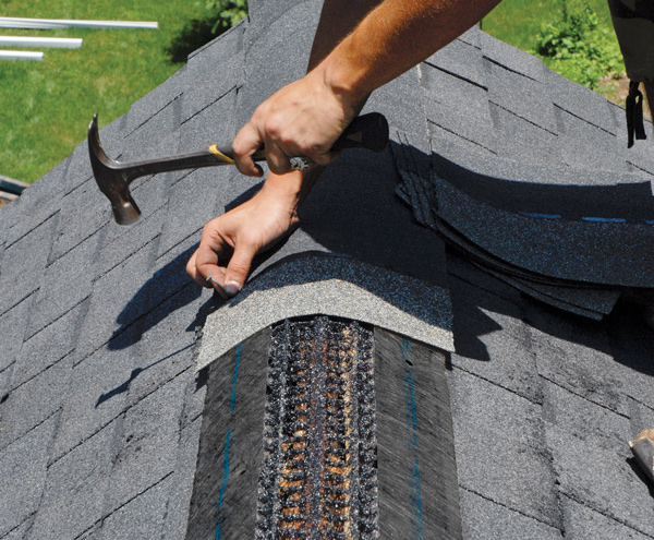 Shingles being nailed over newly installed ridge cap vent product